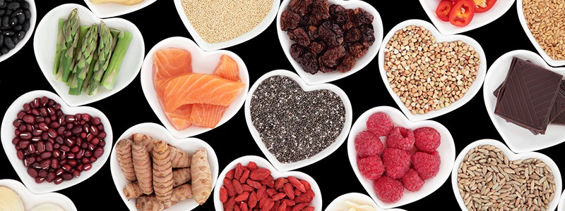 Healthy Nutrition Healthy nutrition of superfood vegetable and fruit selection in heart shaped porcelain dishes over black background, high in vitamins and antioxidants.