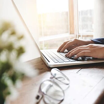 image of woman hands using / typing on laptop computer selected focus on keyboard