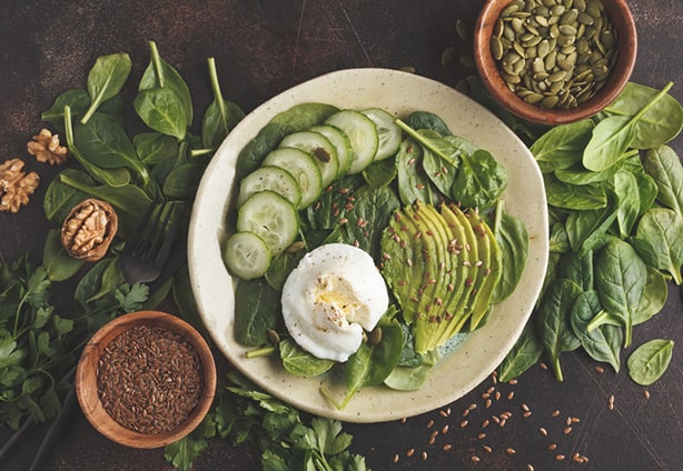 Green salad with spinach, cucumber, avocado, egg, flax and pumpk Green salad with spinach, avocado, egg, flax and pumpkin seed. Food background. Detox Vegetarian Healthy Food Concept. Top view, copy space.